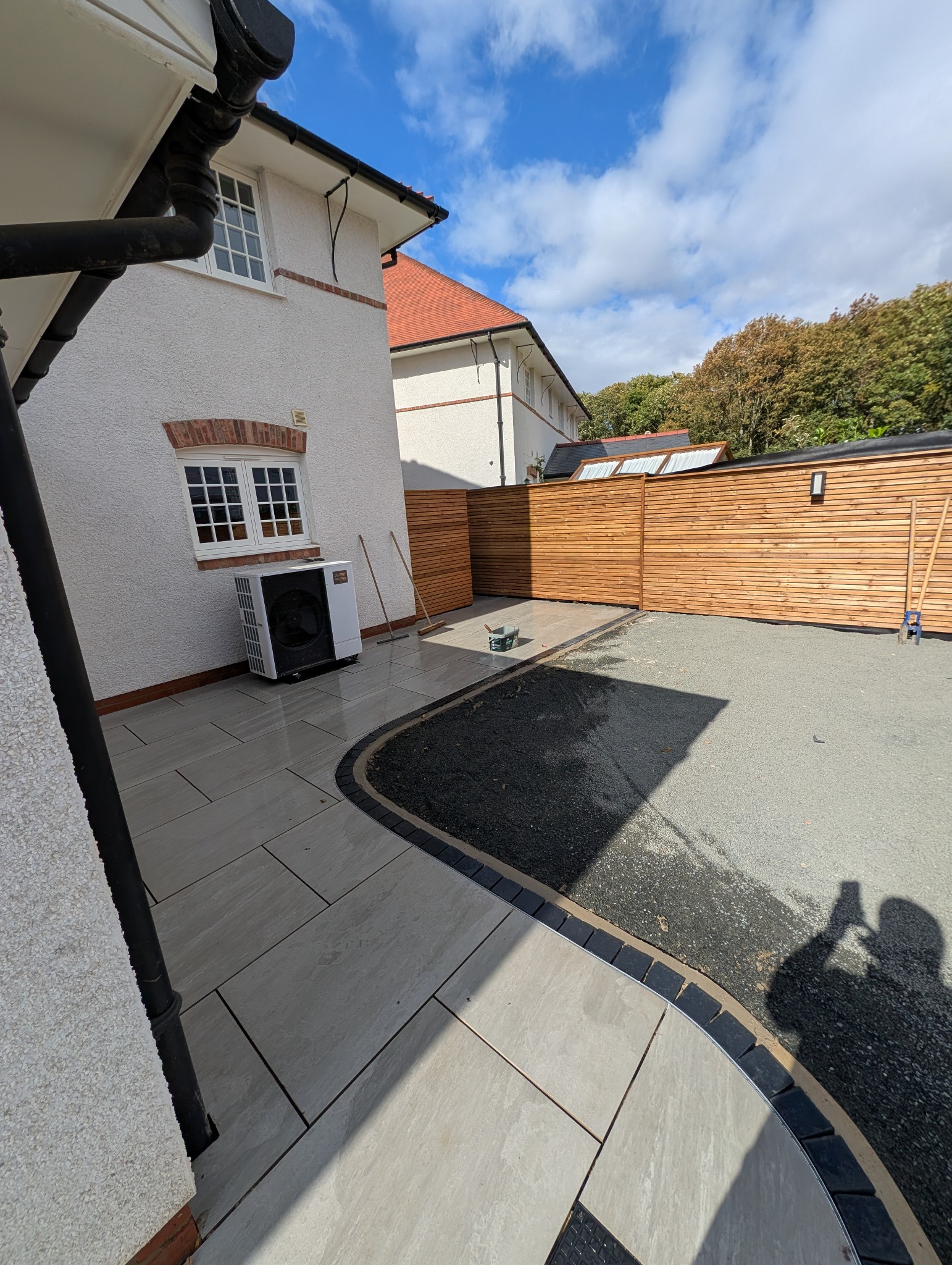 Detailed view of a curved dark border and integrated lighting channel between pale paving and the prepared central garden area