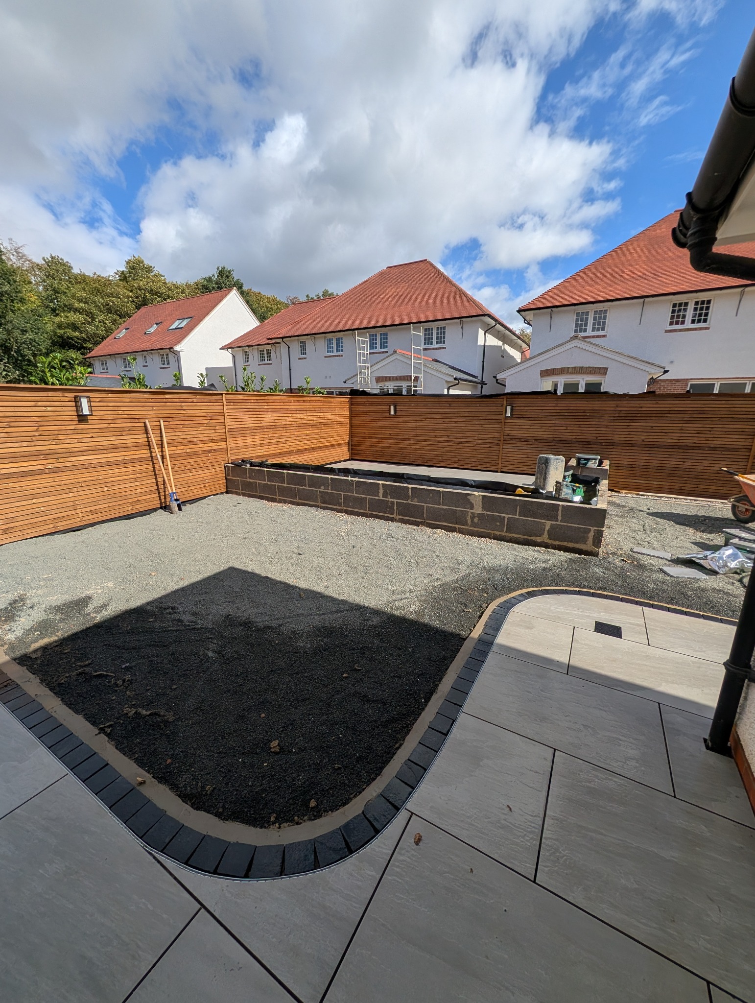 Garden paving with a manhole cover incorporated into the layout beside a curved contrasting border