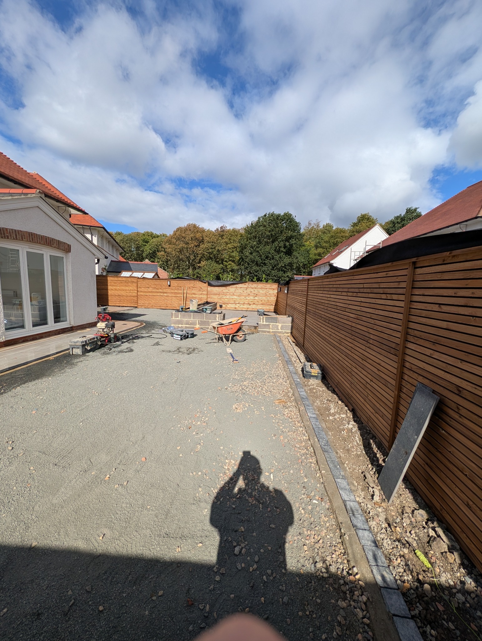 Wide view of the Greenfingers garden project showing the paved terrace, timber screening and prepared central landscaped area